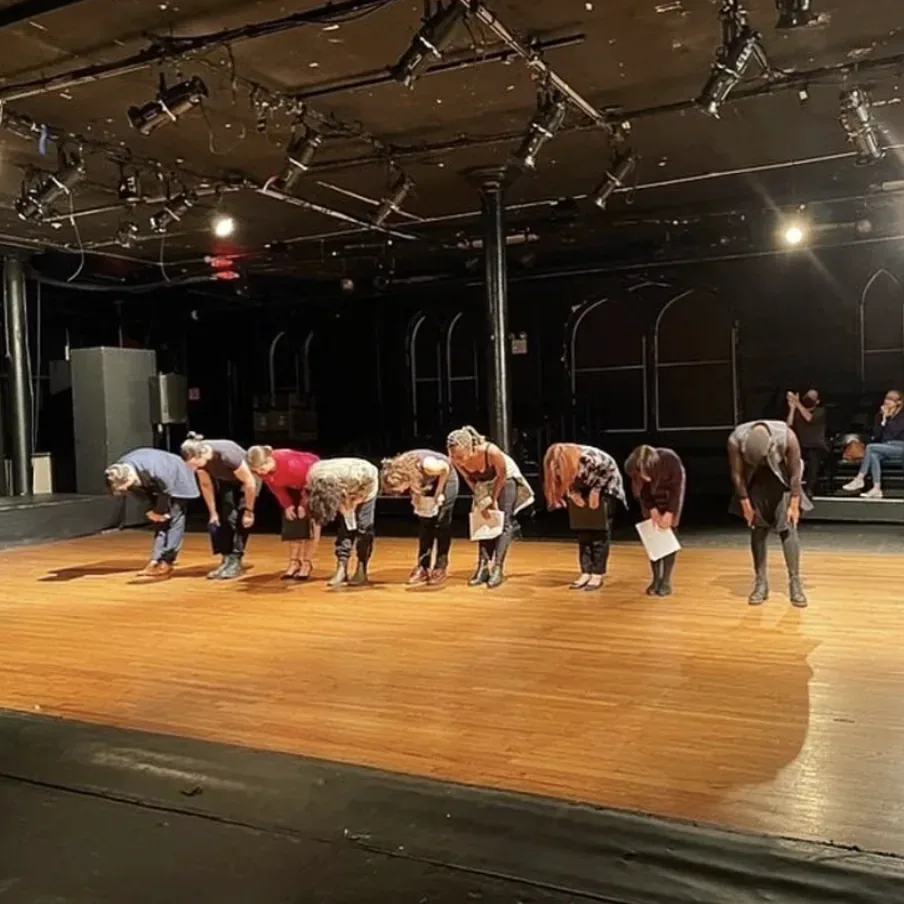 Production photo — the nine-person cast lined up across the stage taking their bow