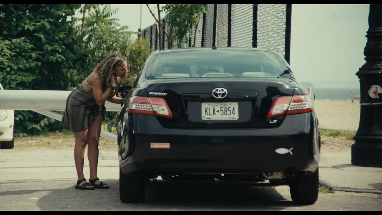Perfect Love still — a woman leaning into a car window by the beach